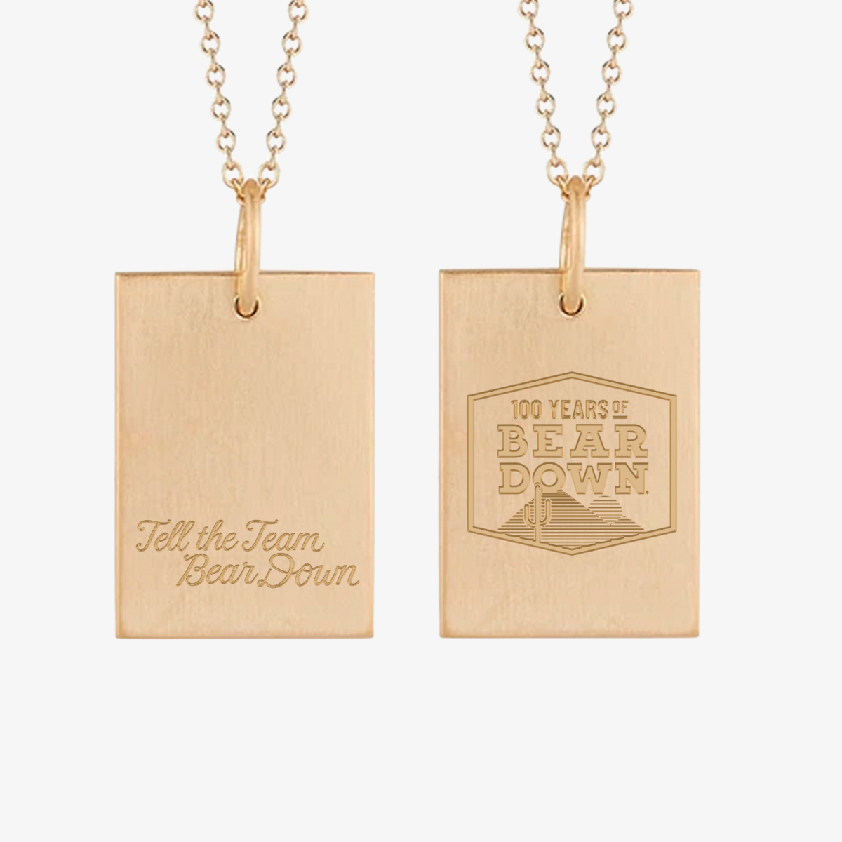 Two gold rectangular pendant necklaces shown side by side on a light gray background. The left pendant is brushed gold with the engraved script text 'Tell the Team Bear Down.