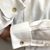 Close-up of a white dress shirt with a spread cuff and a gold-toned cufflink, worn on a person's arm.