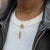 UT Tower Necklace shown on figure in gold with Texas Exes Sunburst and Link Chain Choker