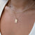 Close-up of a person wearing a gold necklace with a tag pendant on a white background