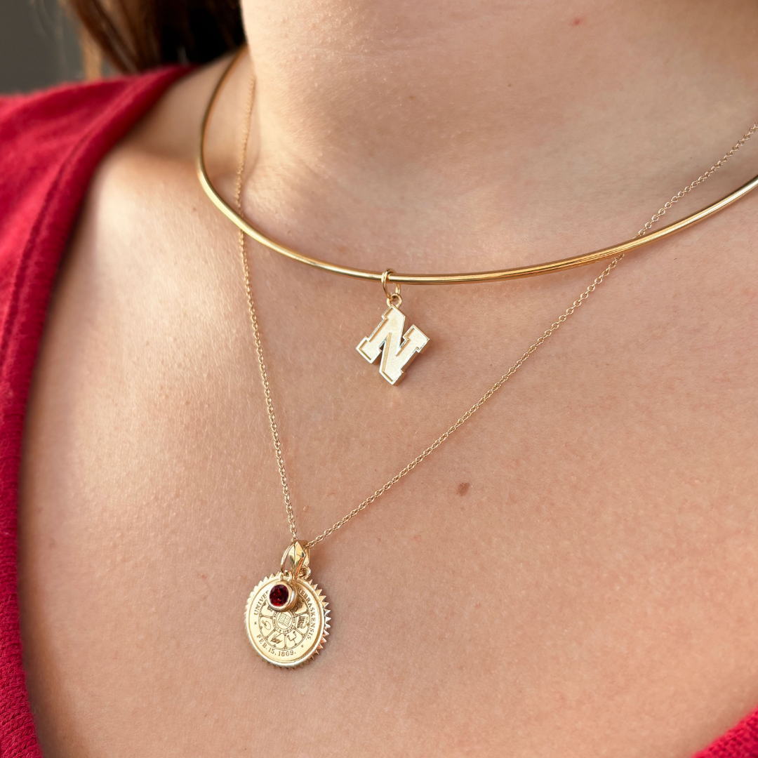 Nebraska Logo Charm shown on figure in gold on Neck Collar with Nebraska Sunburst Bundle 