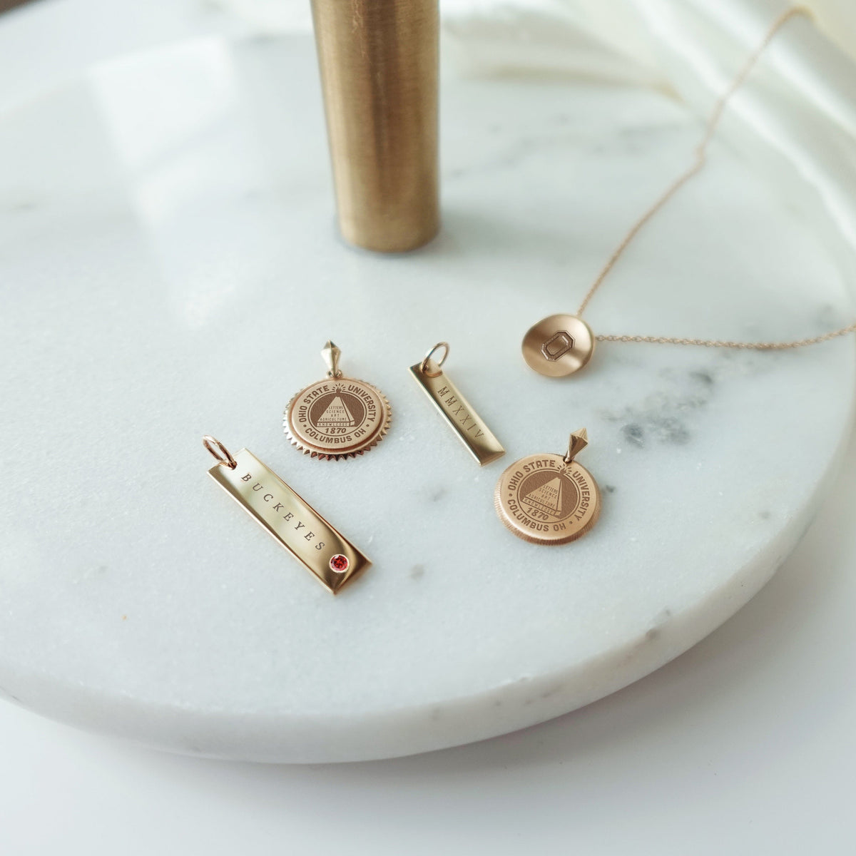 Ohio State collection featuring the Buckeyes Garnet Bar, Ohio State Sunburst, 2024 Bar, Ohio State Florentine, and Ohio State O Organic Necklace Petite laydown shown in gold