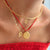 Layered gold necklaces worn by a model, including a thin chain, a bangle-style chain with a geometric pendant, and a chain with a small arch and a round medallion pendant, paired with a red lace top.