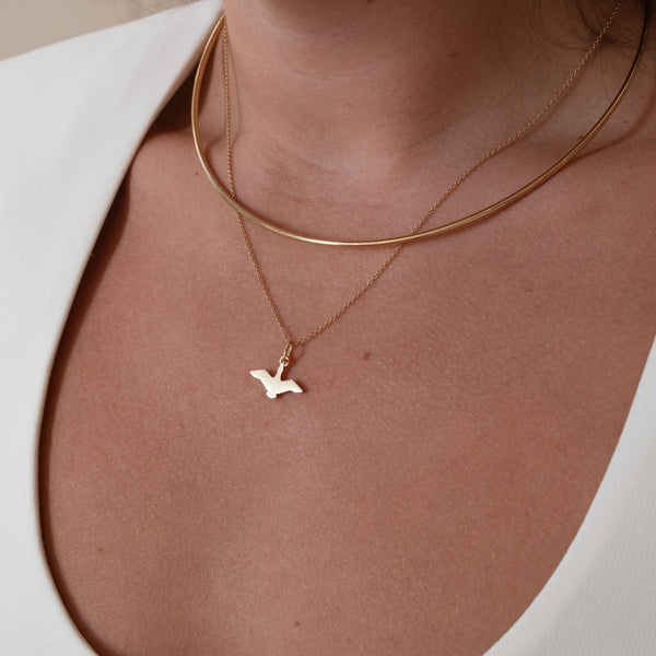 Oregon Flying Duck Charm shown on figure in gold on Cable Chain, layered with Neck Collar in gold