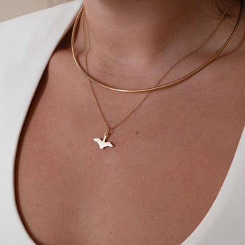 Oregon Flying Duck Charm shown on figure in gold on Cable Chain, layered with Neck Collar in gold