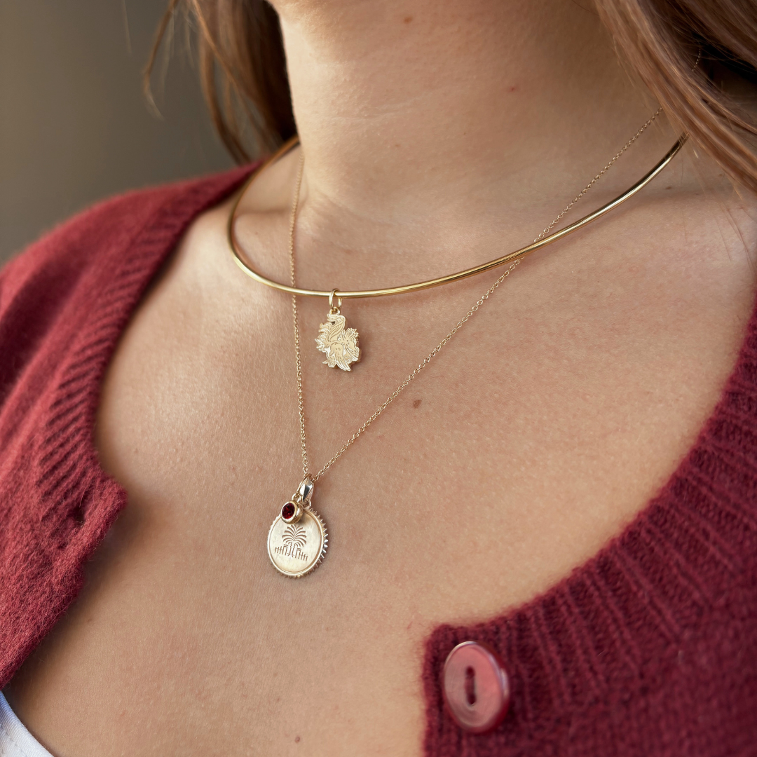 South Carolina Gamecock Charm shown on figure in gold on Neck Collar with South Carolina Palm Sunburst and Garnet Gemstone on Cable Chain in gold
